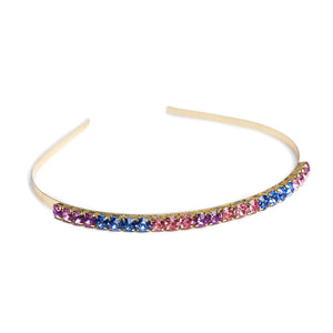 A multicolored chunky gem headband with a metallic band and studded with pink, purple, and blue gems.