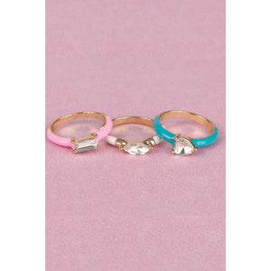 A set of three rings with gold-colored bands and crystal accents, displayed in pink and blue colors.