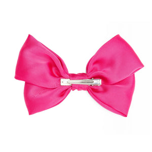 A vibrant hot pink colored hair clip in a bow shape with a central attachment point, designed for use in cheerleading or dance.