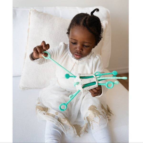 Child playing with a green toy on a white couch