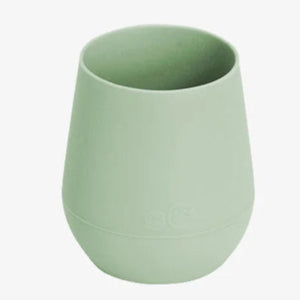 A green ezpz Tiny Cup designed for infants 4+ months to help transition from bottle to cup.