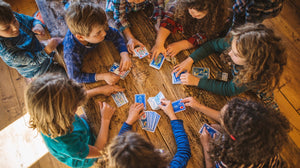Children playing cards around a wooden table