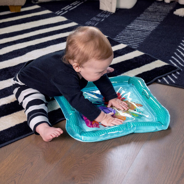 Baby playing with an inflatable activity mat on a striped rug