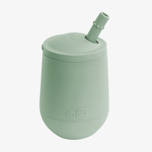 A green silicone mini cup with a straw attached to the lid, designed for toddlers.