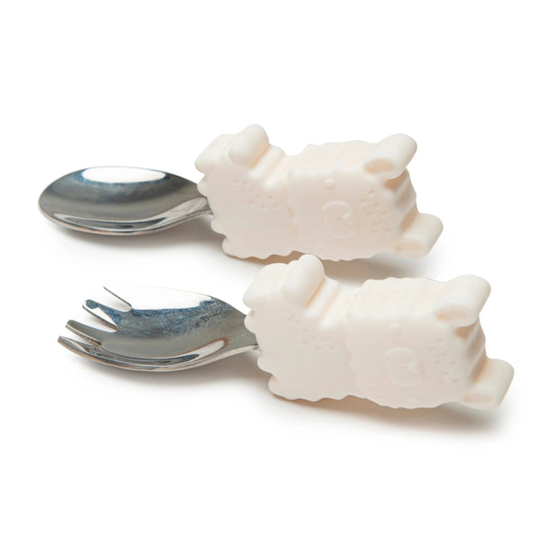 A toddler fork and spoon set with animal character designs on the handles, made of silver and white silicone.
