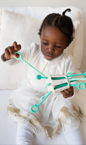 Child playing with a green toy on a white couch