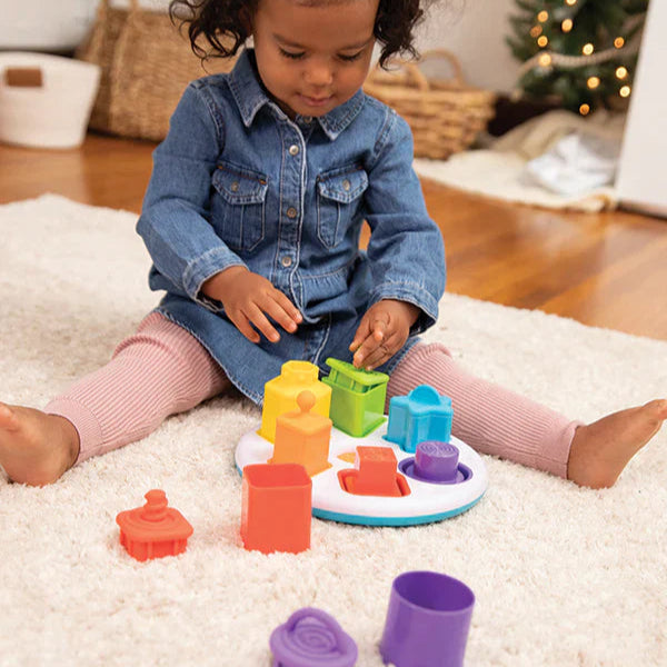 Child playing with colorful toys on a carpeted floor.
