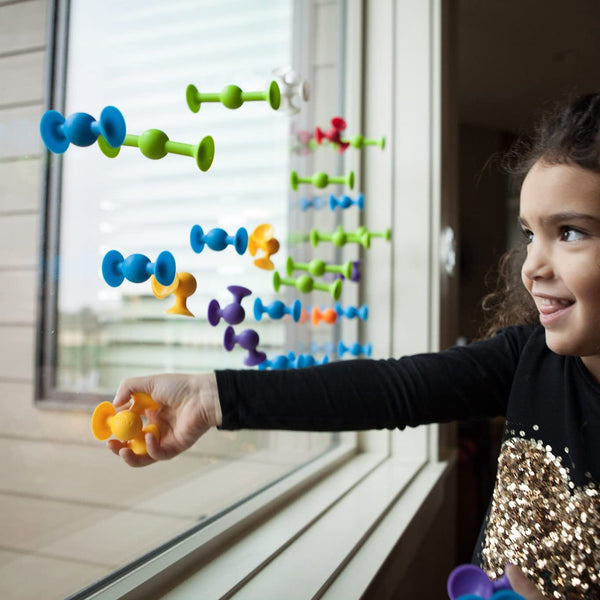 Child playing with colorful magnetic toys on a window