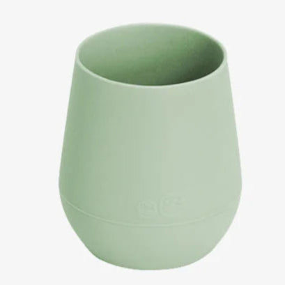 A green ezpz Tiny Cup designed for infants 4+ months to help transition from bottle to cup.
