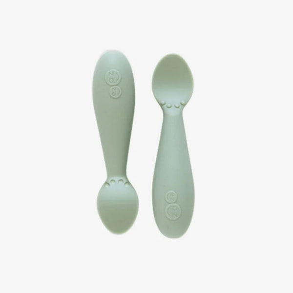 Two silicone baby spoons in a light green color, designed for self-feeding infants.