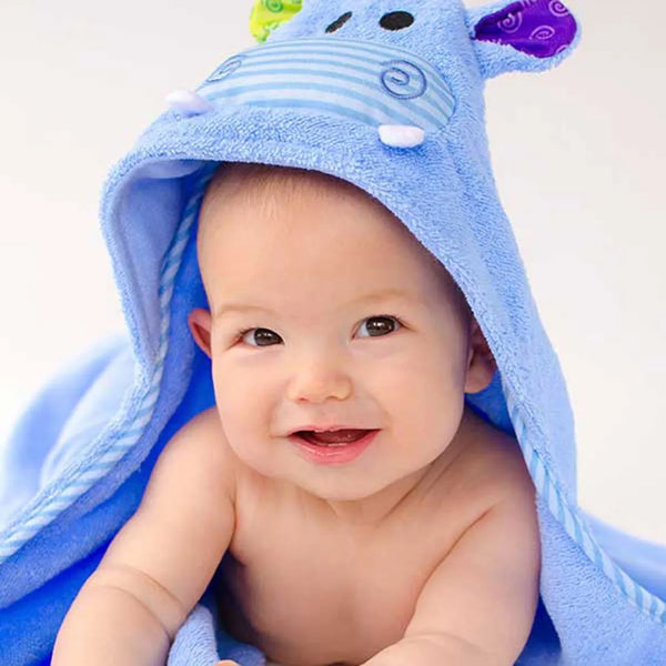 A baby hooded towel with a character design, predominantly blue, being worn by a smiling infant.