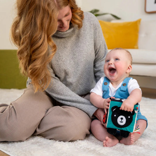 Woman sitting on the floor with a baby holding a toy, in a home setting.