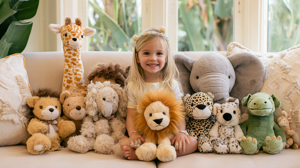 Child sitting on a couch with a collection of Aurora stuffed animals