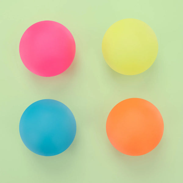 Four matte colored balls arranged in a 2x2 grid on a pale mint green background: pink, yellow, blue, and orange.