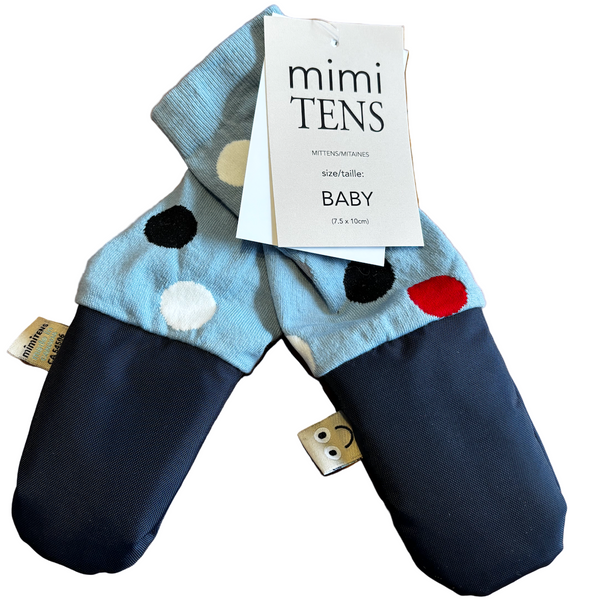Pair of baby mittens with polka dot pattern on a wooden surface, featuring a 'mimi TENS' label.