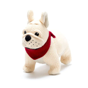 A knitted plush toy resembling a beige dog with a red scarf.