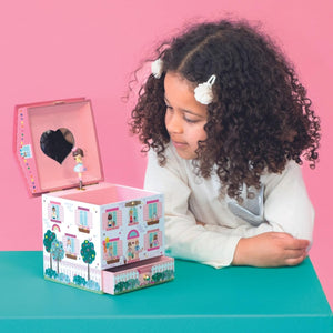 Child playing with a music box against a pink background