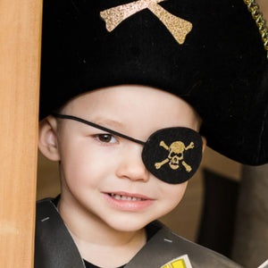 A child dressed as a pirate wearing a black eye patch with a skull and crossbones design.