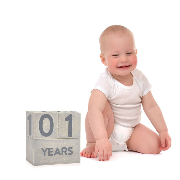 Baby sitting next to a block set displaying '101' on a white background