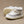 Pair of white baby booties with fuzzy texture on a beige background
