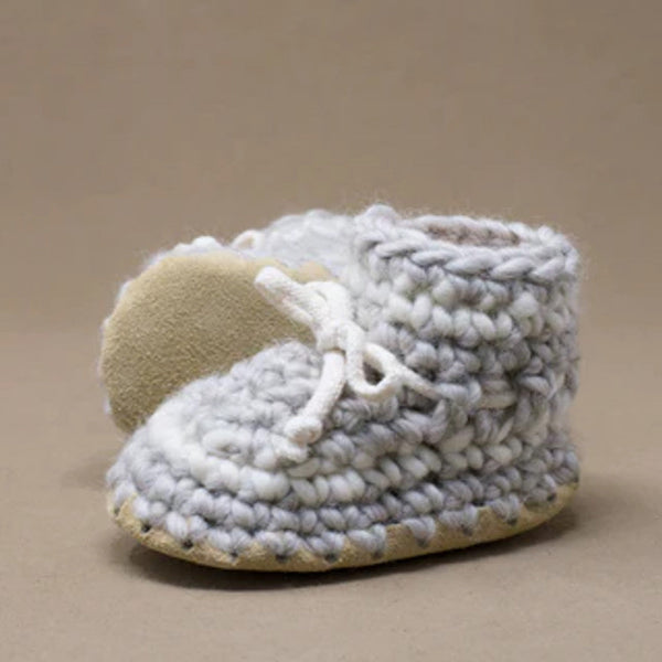 Pair of knitted baby booties on a beige background