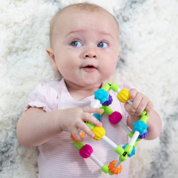 Baby playing with a colorful toy on a soft surface