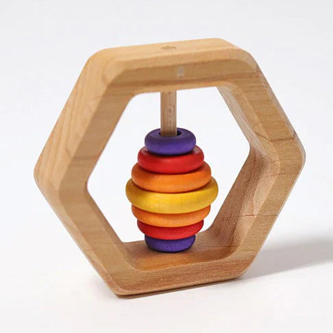 Wooden toy with rainbow-colored rings inside a hexagonal wooden holder on a white background