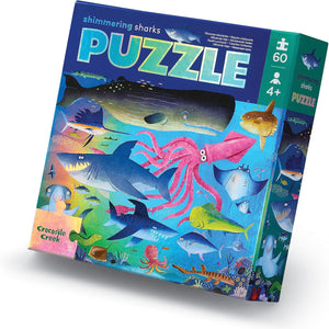 A box of Crocodile Creek Shimmering Sharks Foil Puzzle featuring various colorful sea creatures, including sharks, printed on holographic foil.